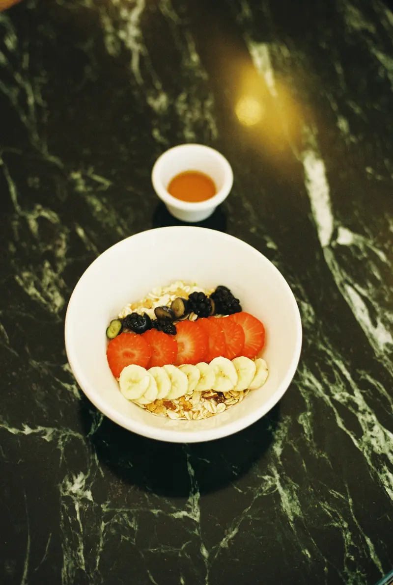 Bol de yogur con granola y fruta sobre una mesa de mármol oscuro