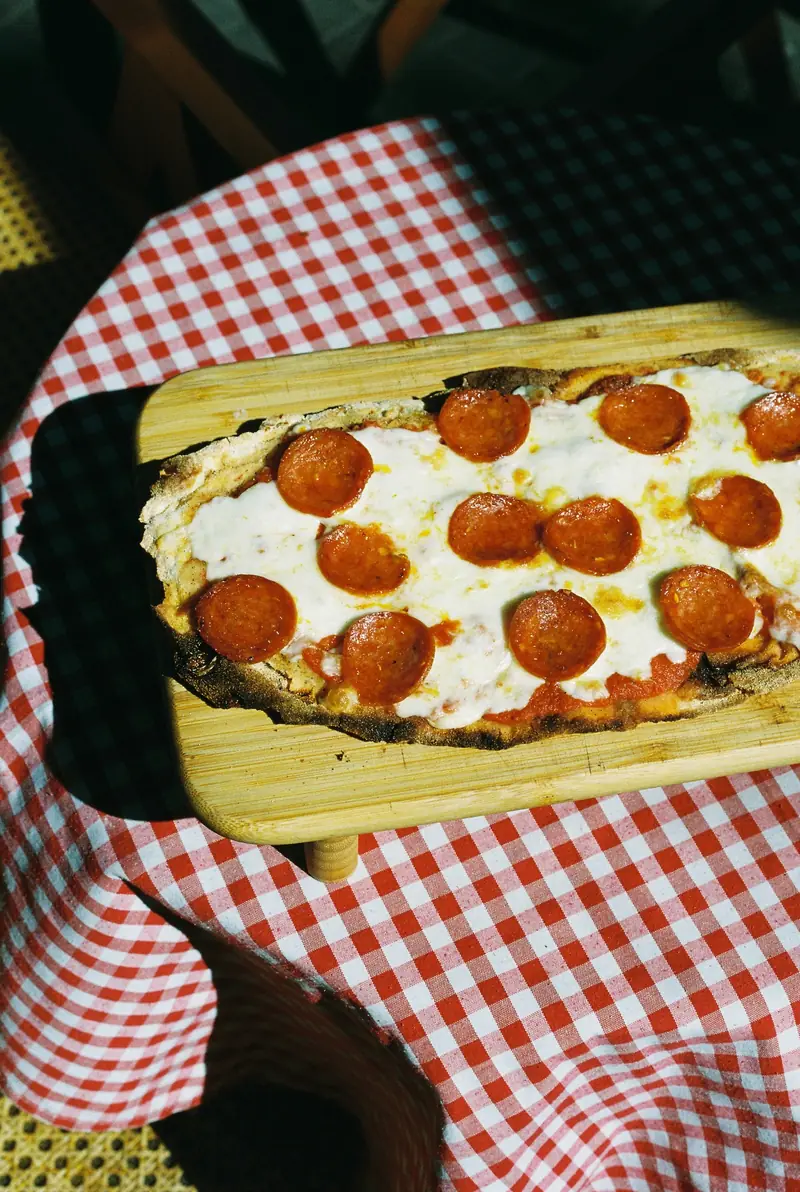 Pizza diavola con rodajas de salami picante sobre una tabla de madera