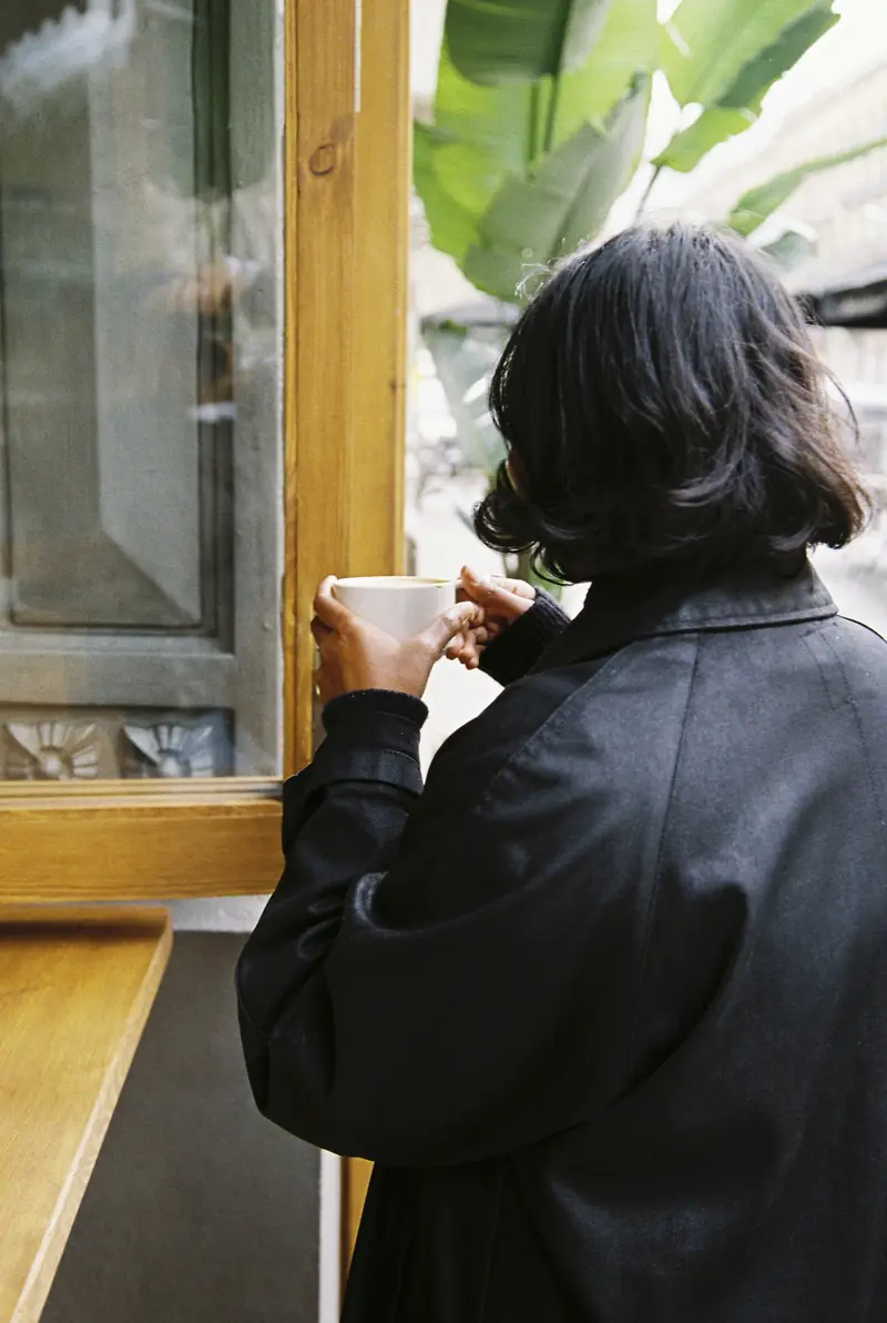 Una persona toma un café junto a la ventana del local